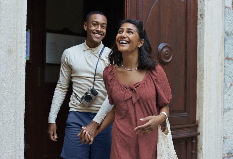 A vacationing couple holding hands and laughing